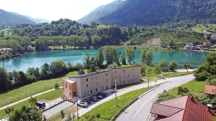 The hotel before its refurbishment, beside the turquoise Soča river with wooded hills behind