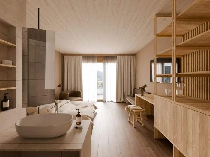 Hotel room clad in light timber, with a freestanding basin, a bed and a balcony door onto the valley
