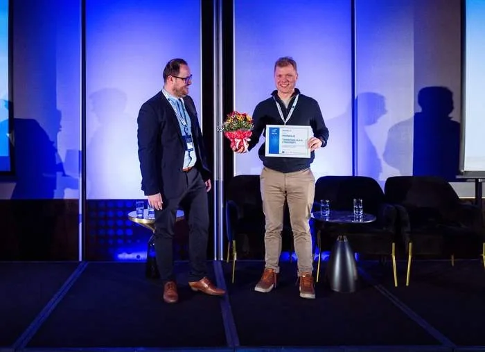 Receiving the award certificate and a bouquet on a blue-lit stage