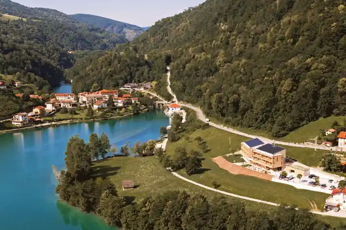 Zračni posnetek doline Soče z leseno stavbo hotela na pobočju nad reko